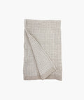 A folded beige waffle‑weave towel with a textured pattern, displayed against a white background.  | Wildwood Home Co.